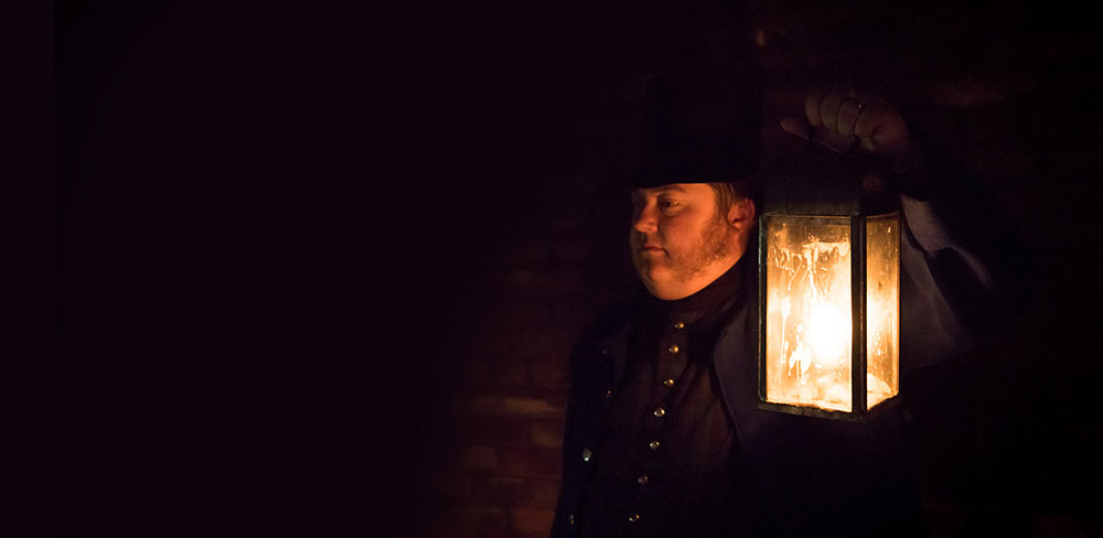 A man directing the ghost tours in the night with a lantern